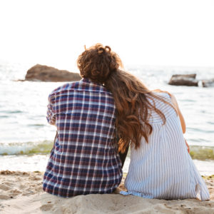 Beautiful young couple sitting together on the beach