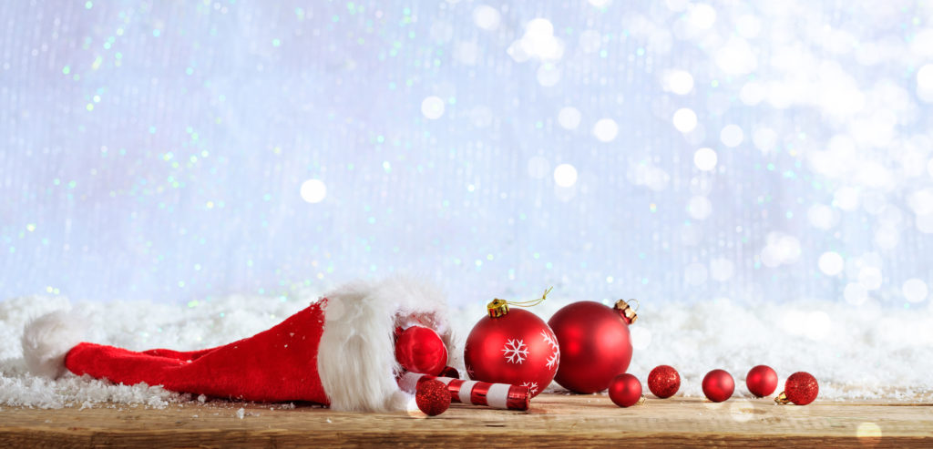 Christmas ornaments and santa hat on wooden snowy background