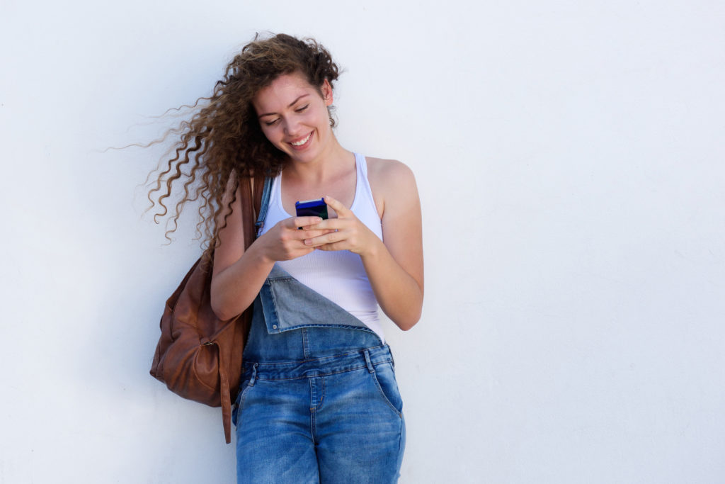 Portrait of happy young girl on cellphone texting