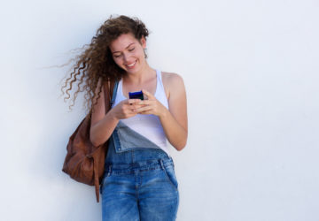 Portrait of happy young girl on cellphone texting