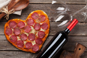 Heart shaped pizza with wine glasses and bottle