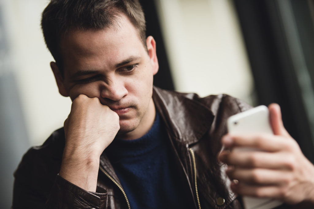 Portrait of tired young businessman texting