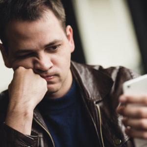 Portrait of tired young businessman texting