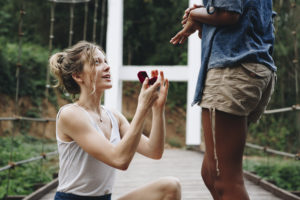 Woman proposing to her happy girlfriend outdoors love and marriage