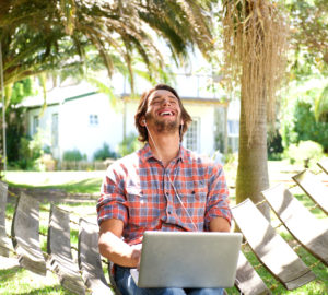Young man laughing with laptop outdoors