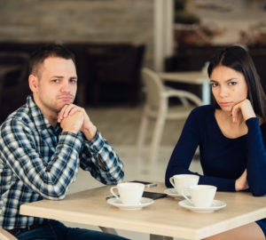 Young unhappy married couple having serious quarrel at cafe